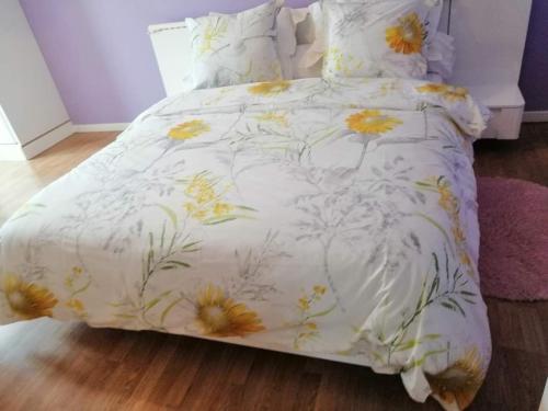 ein Bett mit einer weißen Tagesdecke mit Blumen darauf in der Unterkunft Chambres d'Hôtes Chez Marilou in Aulnay-sous-Bois