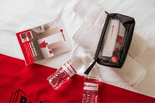 a bottle of toothpaste and a bottle of water on a bed at RedDoorz @ Sekip Medan in Medan