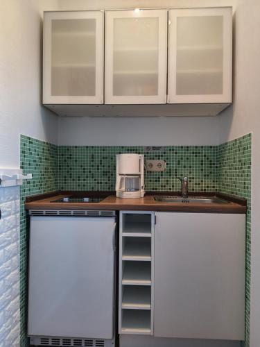 a kitchen with white cabinets and a sink at Haus Achtern Diek in erster Reihe am Meer in Fehmarn