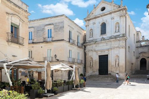 een groep gebouwen met mensen die op een binnenplaats lopen bij Palazzo Charlie in Lecce