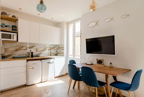 a kitchen with a wooden table and blue chairs at Appartement le Quai du Port Cassis parking clim in Cassis
