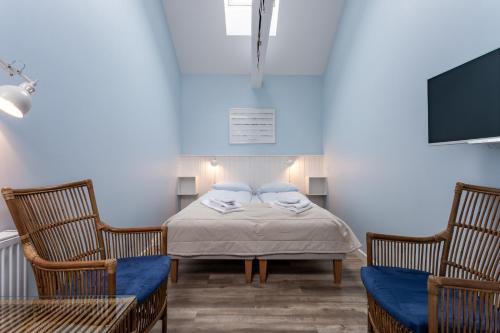 a small bedroom with a bed and two chairs at Rødvig Kro og Badehotel in Rødvig