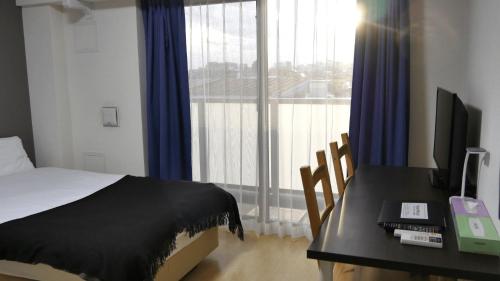 a bedroom with a bed and a desk with a computer at Universal Haneda in Tokyo