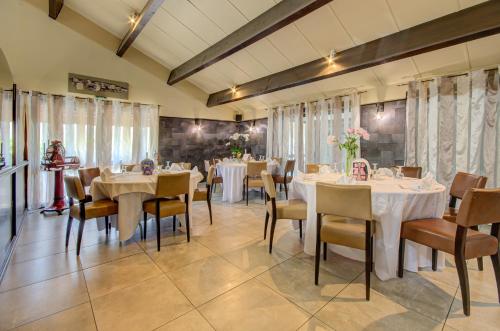 a dining room with white tables and chairs and windows at Eurotel Parc Expo Airport Montpellier in Pérols