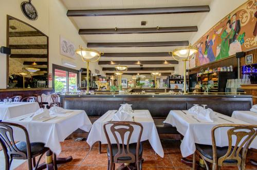 a restaurant with white tables and chairs and a bar at Eurotel Parc Expo Airport Montpellier in Pérols
