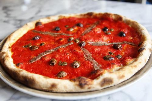 a pizza sitting on a plate on a table at Lo Scoiattolo Piedmont Bike Hotel in Pralormo