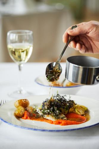 a person holding a spoon over a plate of food at Rødvig Kro og Badehotel in Rødvig