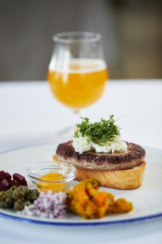 a plate of food with a sandwich and a glass of beer at Rødvig Kro og Badehotel in Rødvig