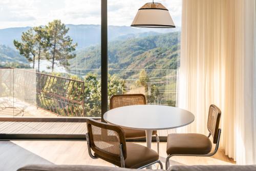 a room with a table and chairs and a large window at Encosta de Louredo by Pousadela Village in Vieira do Minho