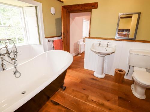 a bathroom with a tub and a toilet and a sink at Eagle Farmhouse in Glenridding
