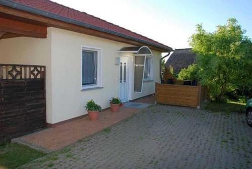 ein weißes Haus mit einem Tor und einer Auffahrt in der Unterkunft Ferienhaus Guenter in Gager