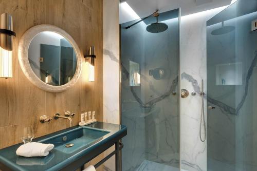 a bathroom with a glass shower and a sink at La Demeure Montaigne in Paris