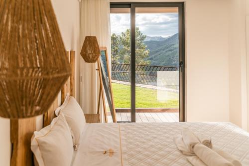 a bedroom with a bed with a view of a balcony at Encosta de Louredo by Pousadela Village in Vieira do Minho