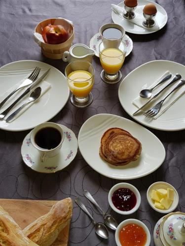 una mesa con platos de comida y tazas de café en Domaine de Pelouaille - chambre d'hôtes, en Saint-Jean-dʼAngély