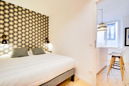 une chambre avec un grand lit blanc et une chaise dans l'établissement Le Cachet de la Craffe - Au cœur de Nancy, à Nancy