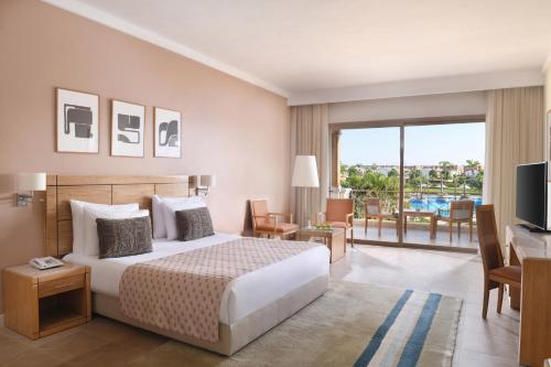 a bedroom with a bed and a television and a balcony at JAZ Little Venice Golf Resort in Ain Sokhna