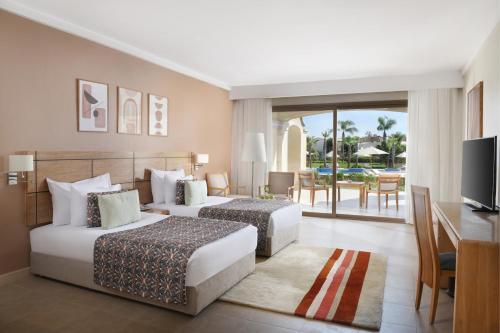 a hotel room with two beds and a desk and a television at Jaz Little Venice Golf Resort in Ain Sokhna