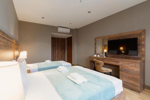 a hotel room with two beds and a television at Cozy Loft Hotel in Batumi