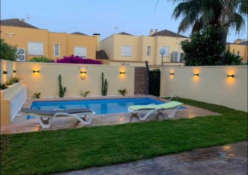 a backyard with a swimming pool and a house at CASA DE LUJO CON PISCINA a 5 minutos andando del recinto ferial in Jerez de la Frontera