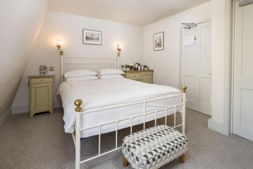 a bedroom with a white bed and a stool in it at Crown Hotel in Stamford