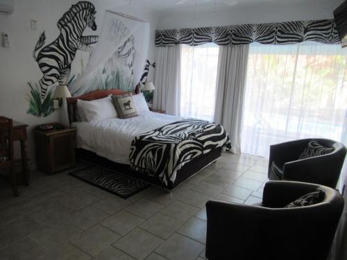 a bedroom with a zebra print bed and two chairs at Bhangazi Lodge Bed & Breakfast in St Lucia