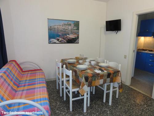 una sala da pranzo con tavolo, sedie e un dipinto di Villa Bianca a Bibione