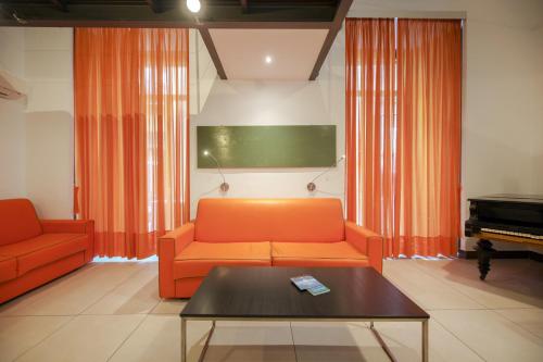 sala de estar con sofá naranja y piano en Residenza Pizzofalcone, en Nápoles
