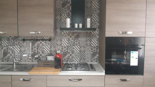 a kitchen with a stove and a black and white wallpaper at Mariam Holiday House in Otranto