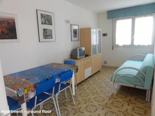 una camera con tavolo, sedie e televisore di Villa Bianca a Bibione