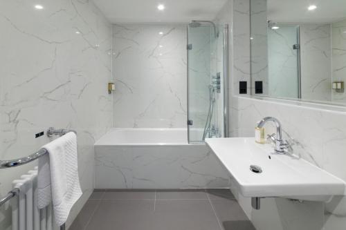 a white bathroom with a sink and a bath tub at Lews Castle in Stornoway