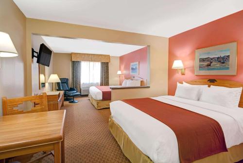 Days Inn & Suites by Wyndham Airport Albuquerque في ألباكيركي: غرفة فندقية بسريرين ومكتب