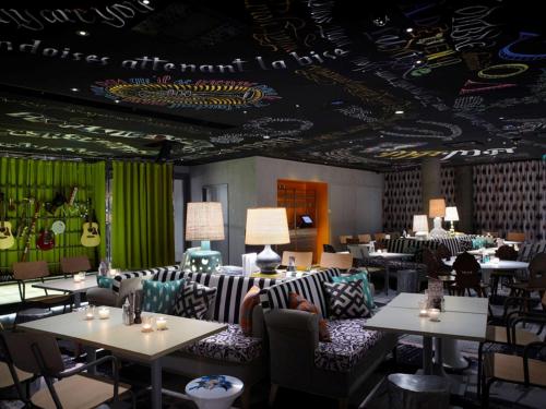 a restaurant with tables and couches and guitars on the ceiling at Mama Shelter Lyon in Lyon