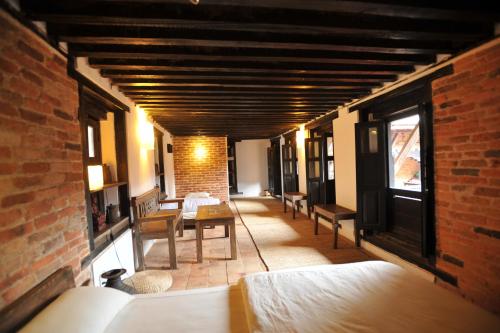 a room with benches and a brick wall at Peacock Guest House in Bhaktapur