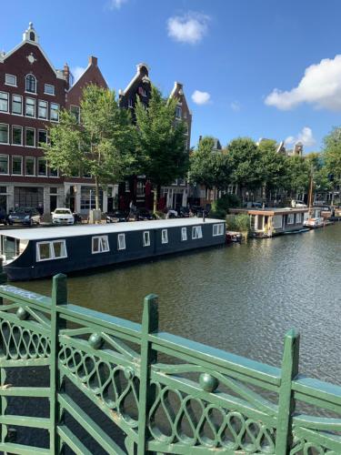 Niebieska łódź jest zacumowana na rzece z budynkami w obiekcie Boat no Breakfast w Amsterdamie