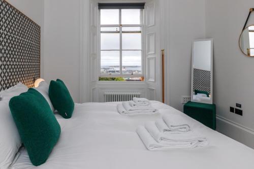 a white bedroom with a large bed with green pillows at Lews Castle in Stornoway