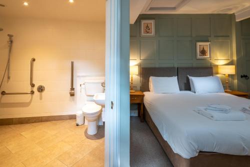 a bedroom with a bed and a bathroom with a shower at The Kings Arms Hotel in Melksham