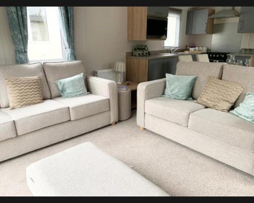 a living room with two couches and a kitchen at Exotic 3-Bed Caravan at Newquay Holiday Park in Newquay