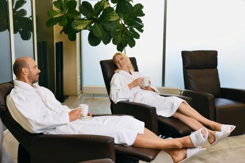 a man and woman sitting in chairs with cups of coffee at Sanatorija ,,Tulpės" in Birštonas