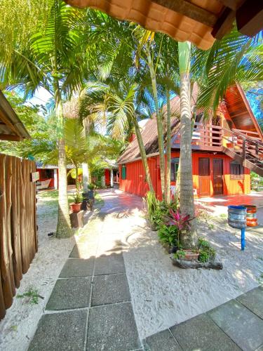 a resort with palm trees and a red building at Pousada Tia Maria in Ilha do Mel