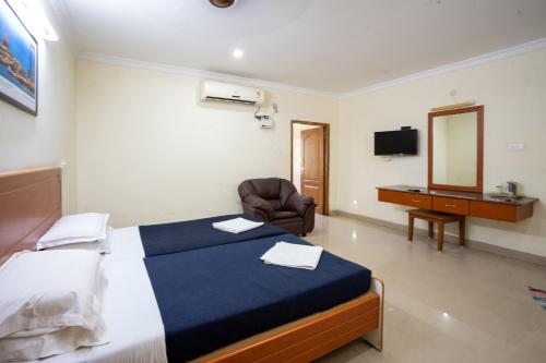 a bedroom with a bed and a chair and a mirror at Hotel TamilNadu -Trichy in Tiruchchirāppalli