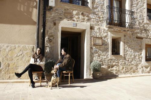 two people and a dog sitting outside of a building at LA MIMBRERA in Estercuel