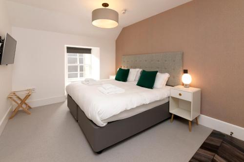 a bedroom with a large bed with green pillows at Lews Castle in Stornoway