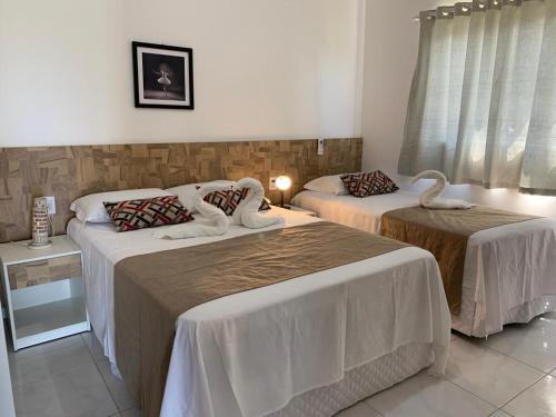 Dos camas en una habitación con dos cisnes. en Casa Porto Fiore en Paripueira