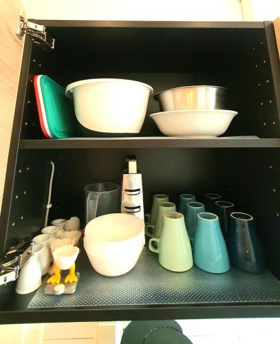 a shelf with bowls and other bowls and utensils at FRANKES CITY SLEEP Apartment, 6 Einzelbetten in Velbert