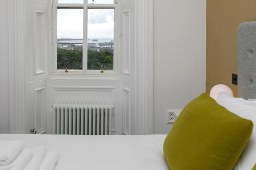 a bed with a green pillow and a window at Lews Castle in Stornoway