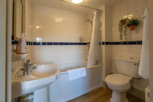 a bathroom with a sink and a toilet and a tub at The Kings Arms Hotel in Melksham