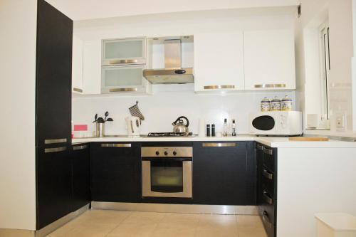 a kitchen with white cabinets and a stove top oven at Modern Apartment in Swieqi Malta in St. Julianʼs