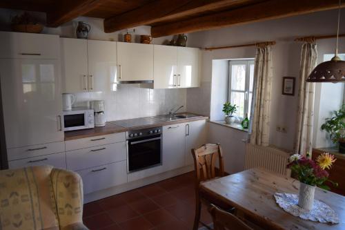 cocina con armarios blancos y mesa de madera en Apartments Bed & Breakfast Brückner, en Willanzheim