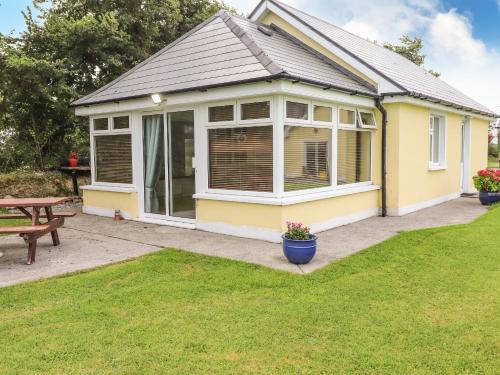 a yellow house with a picnic table in a yard at Moybella Lodge in Ballybunion