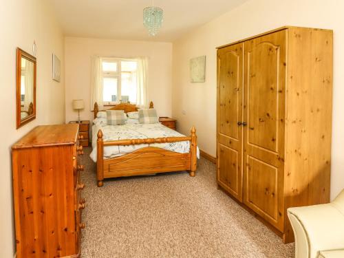 a bedroom with two beds and a large wooden cabinet at Moybella Lodge in Ballybunion
